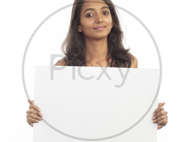 An Indian Female Model In Casual Dress Showing an empty  Placard and Smiling over an isolated White Background