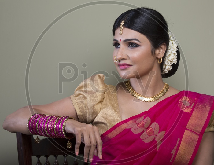 Indian Bride dressed up in red saree portrait in Studio Lighting / Traditionally dressed up girl