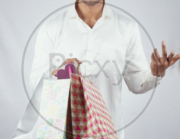 An Indian Male Model In traditional South Indian Attire with Shopping Bags in One Hand and with Smiling Face with expression  on an Isolated White Background