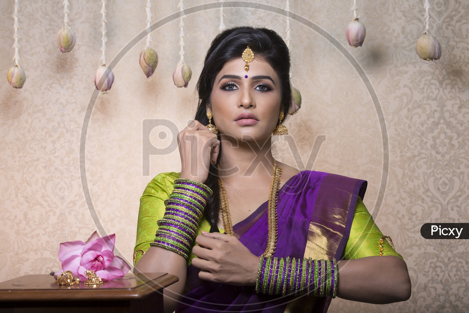 Traditional Indian Female/Woman Model in Purple Saree, green Blouse with a Lotus flower in hand - Posing