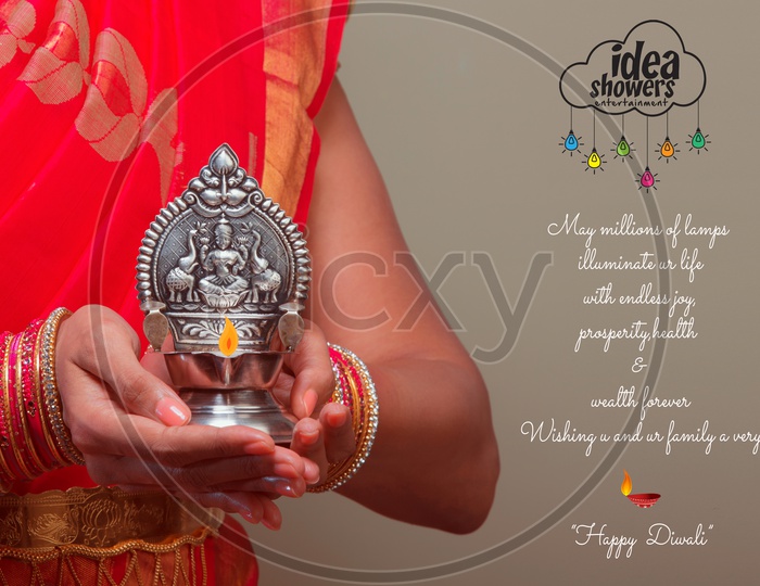 A Beautiful Indian Female Model  in Traditional Attire Wearing a Saree and Jewelry  With a Traditional Silver Oil Lamp In Hands  with Space  Closeup Shot