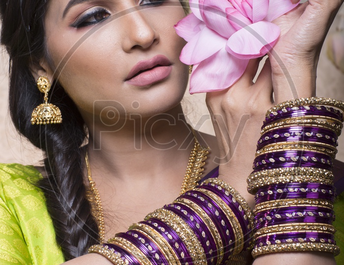 Traditional Indian Female/Woman Model in Purple Saree, green Blouse with a Lotus flower in hand - Smiling