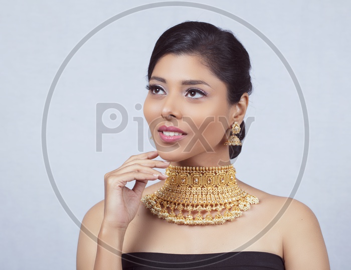 Indian Female Model With a Beautiful  Gold Necklace on Her Neck Looking To Camera And Smiling With An  Expression  On an Isolated White Background