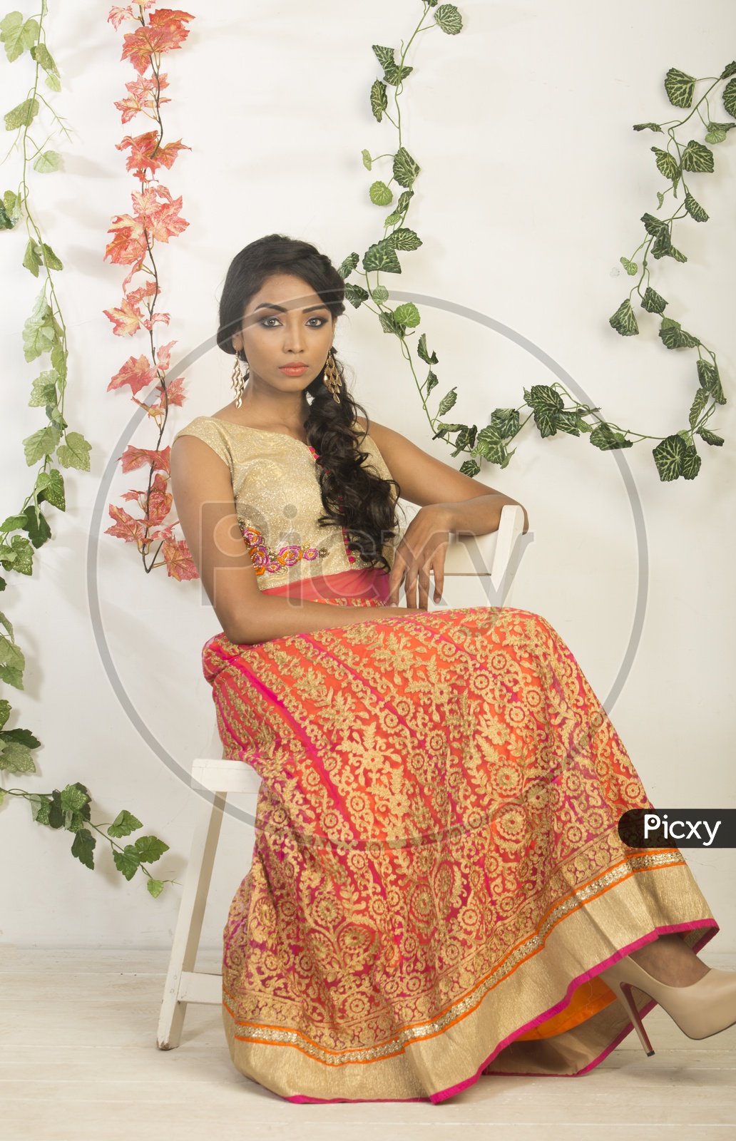 Image of Indian girl dressed up in orange dress portrait in Studio Lighting  / Traditionally dressed up girl-JX610913-Picxy