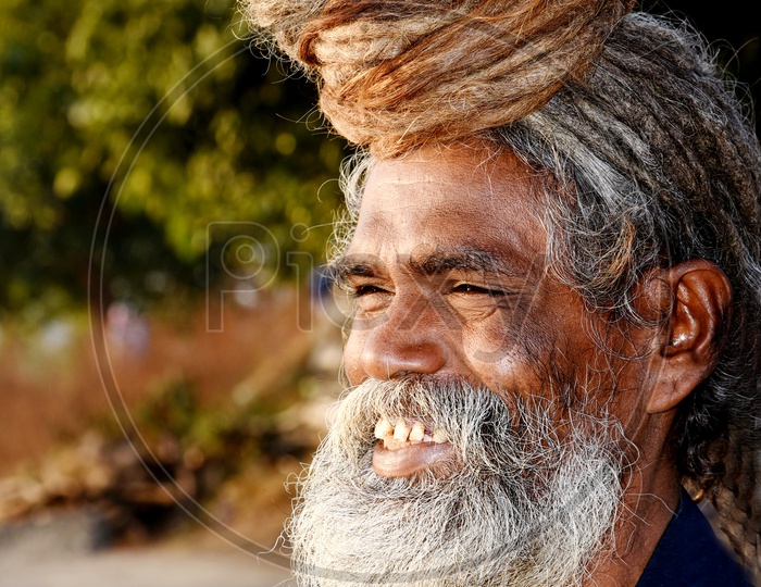 An Indian Old Man With Beard and Long hair Bun Smiling