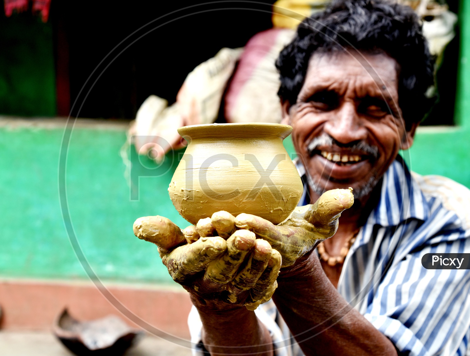 A tribal Village old man Showing The Freshly Made Clay Pot in His Hands