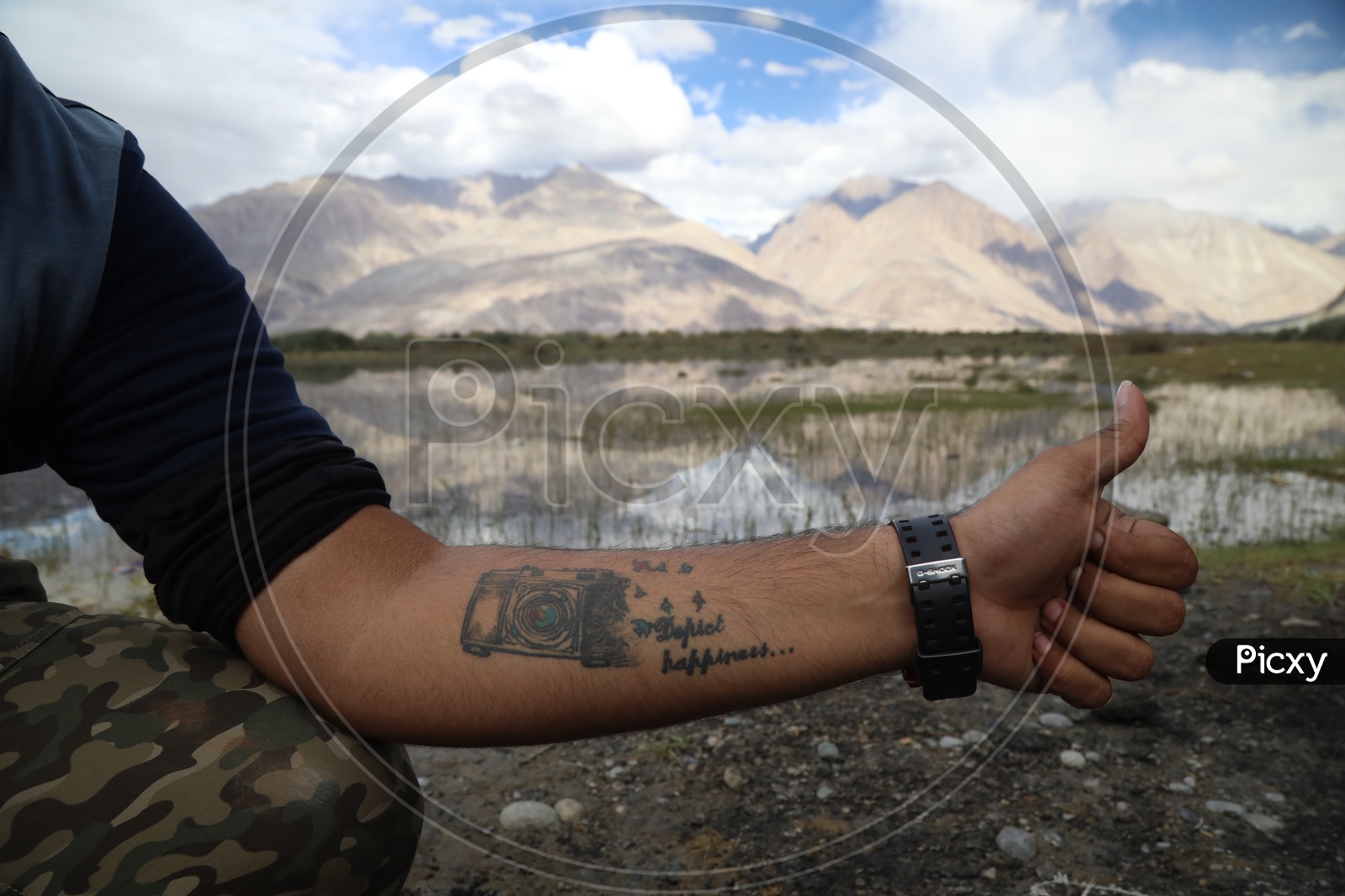 A Photographer With a Camera tattoo on his Hand In River valley of Leh