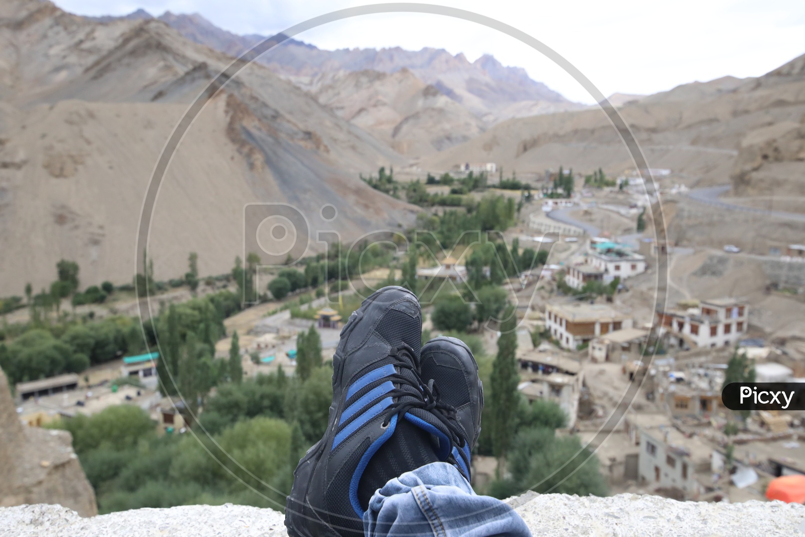 A Composition Shot Of Tourists With Their Legs and Valley Views In Leh