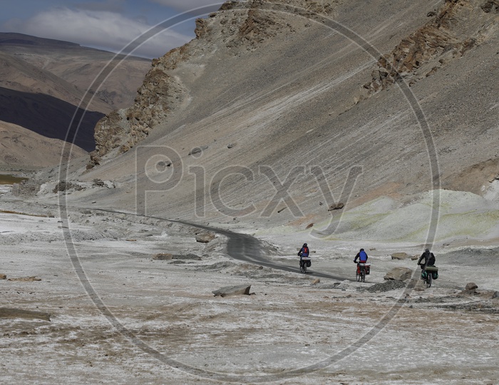 People Commuting by The Cycles On The Roads Of Leh With Sand Dunes in The Background