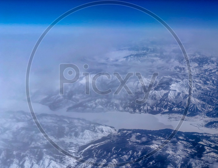 Ariel View of Snow Capped Mountains, Clouds  & Blue Sky