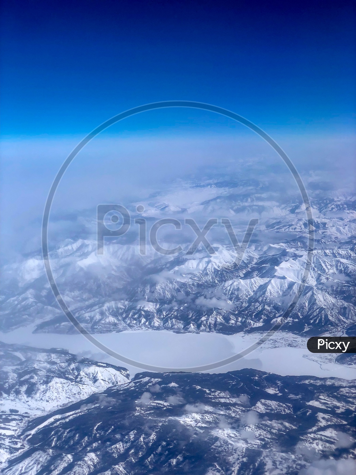 Ariel View of Snow Capped Mountains, Clouds , Blue Sky &  Frozen lake