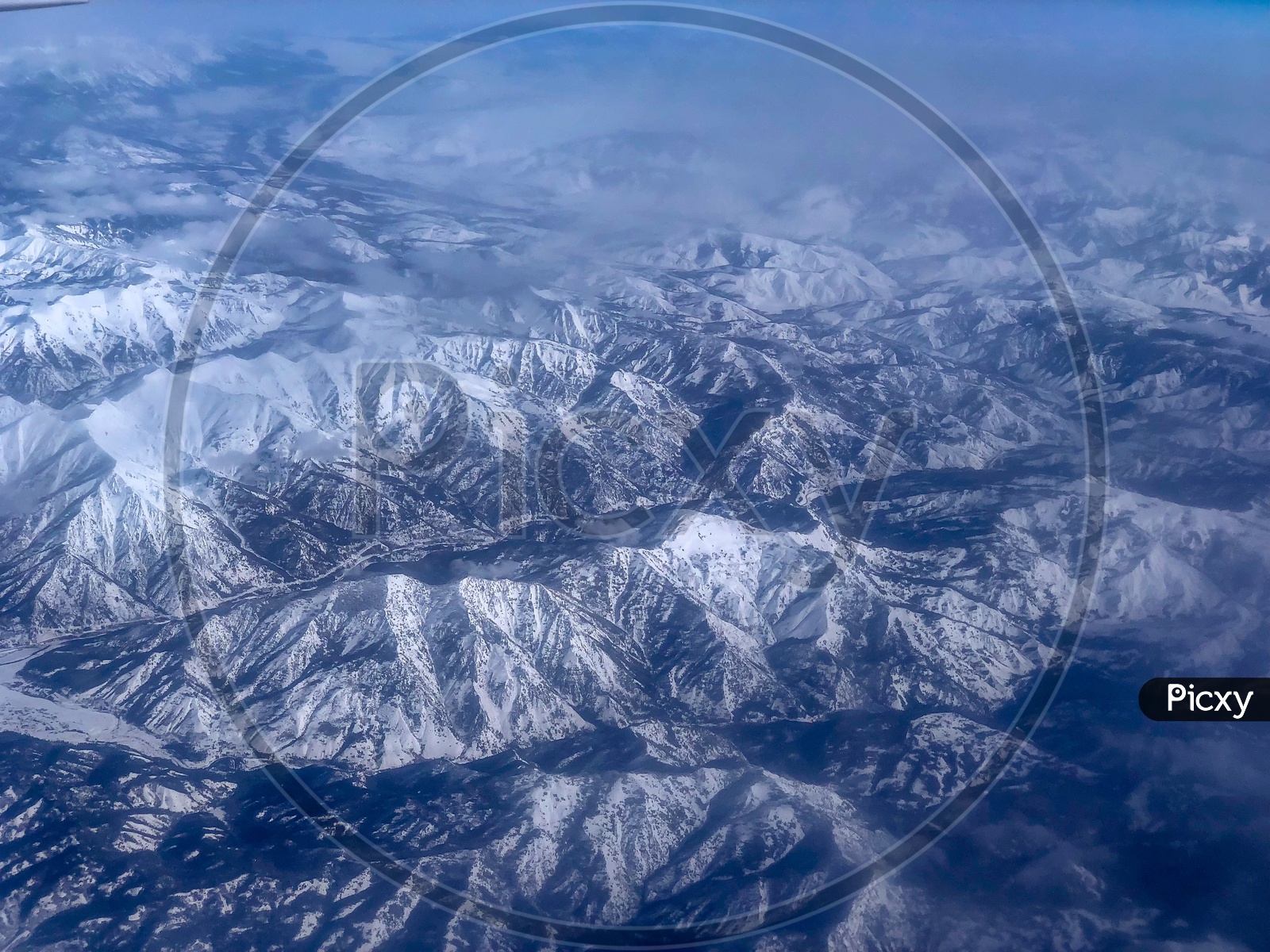 Ariel View of Snow Capped Mountains, Clouds, Blue Sky & Frozen lake