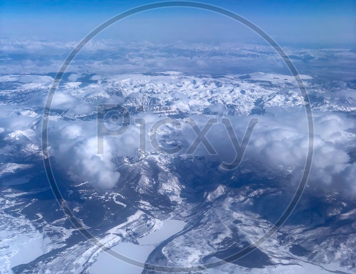 Ariel View of Snow Capped Mountains, Clouds & Blue Sky