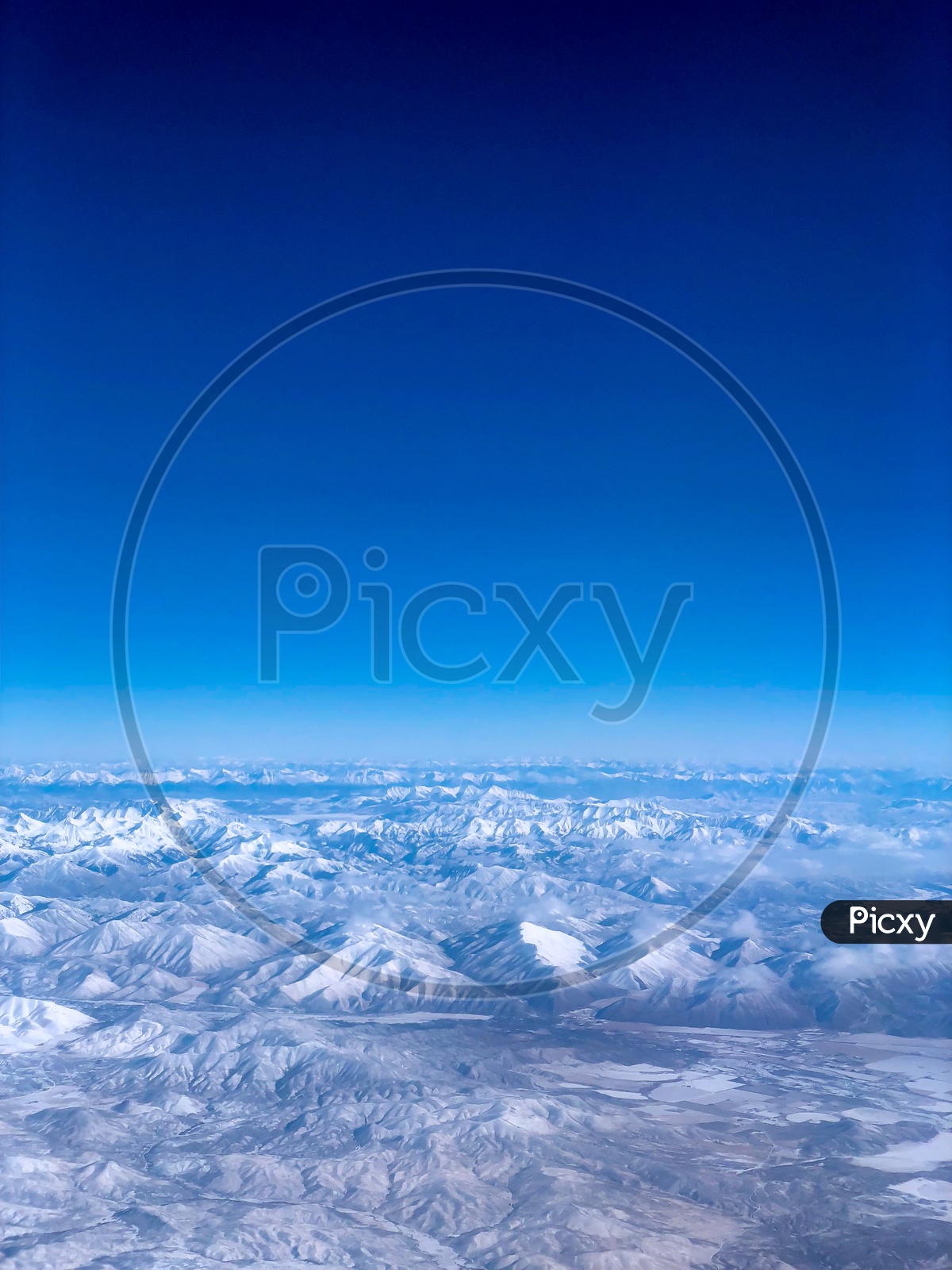 Ariel View of Snow Capped Mountains & Blue Sky