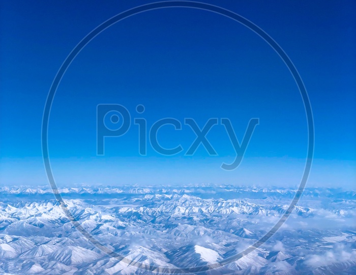 Ariel View of Snow Capped Mountains & Blue Sky