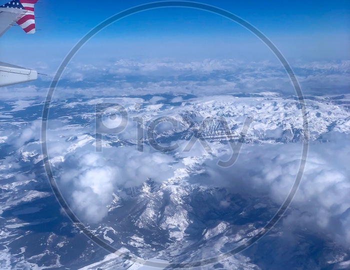 Ariel View of Snow Capped Mountains, Clouds & Blue Sky