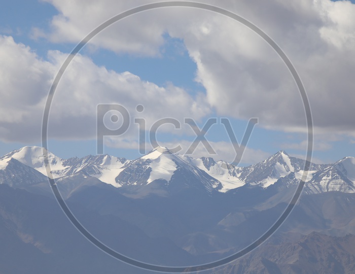 Beautiful Landscape of Snow Capped Mountains of Leh with huge clouds above mountains