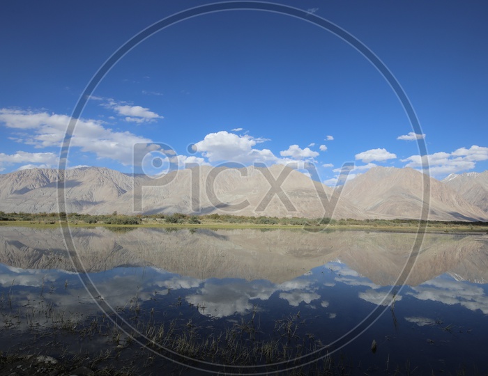 Beautiful Snow Capped Mountains of Leh with lake in the foreground / Himalayan mountains in water reflection