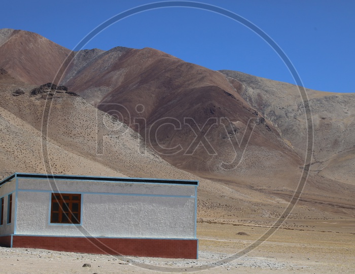 A Lone House In the Valleys Of Leh With Sand Dunes in background