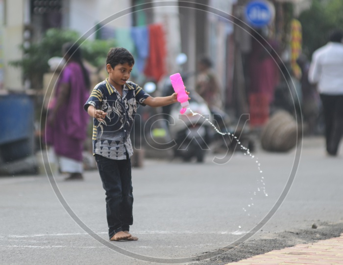 A boy plays with a water bottle  in a street