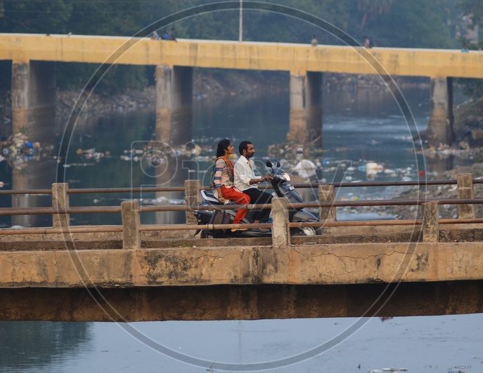 A man rides a motor cycle on a bridge, rivas canal