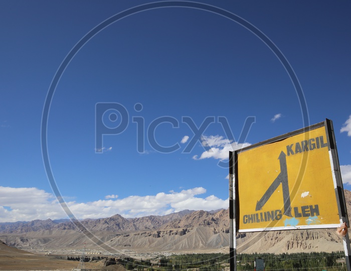Road sign board in leh with snow capped mountains of leh in background
