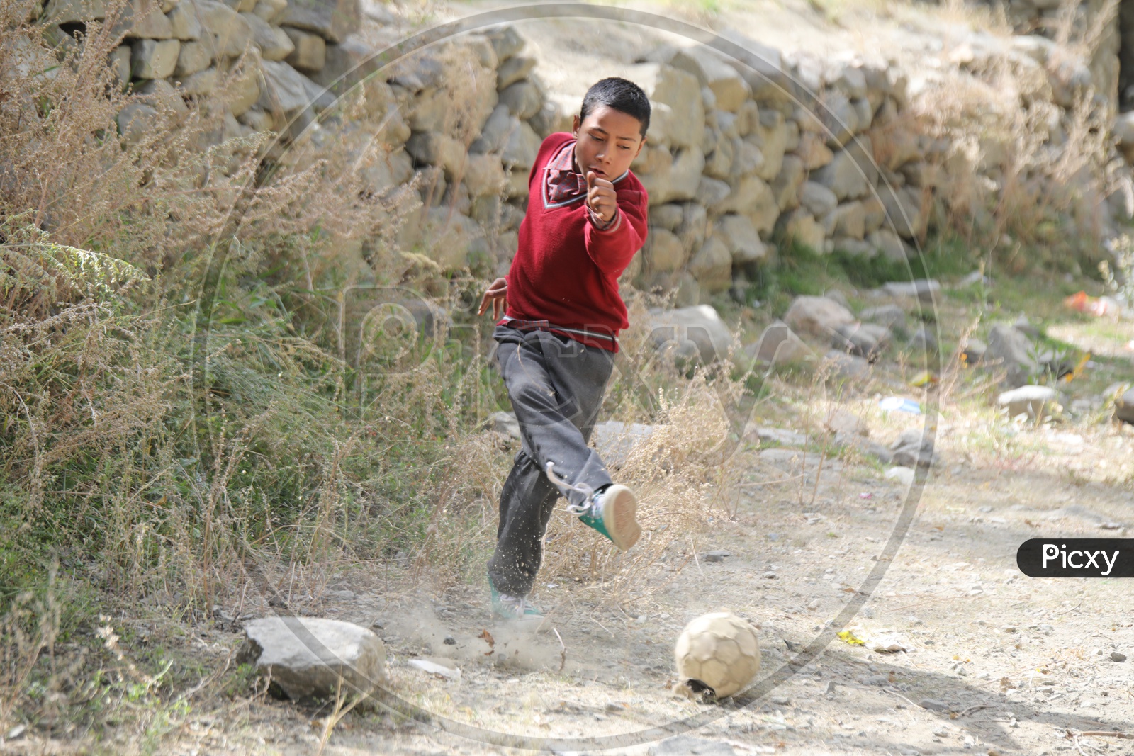 school kid playing football in leh