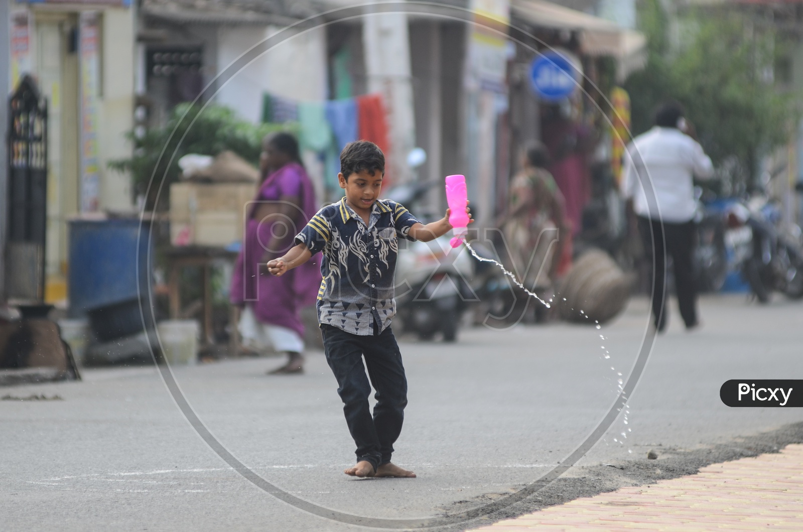 A boy plays with a water bottle  in a street