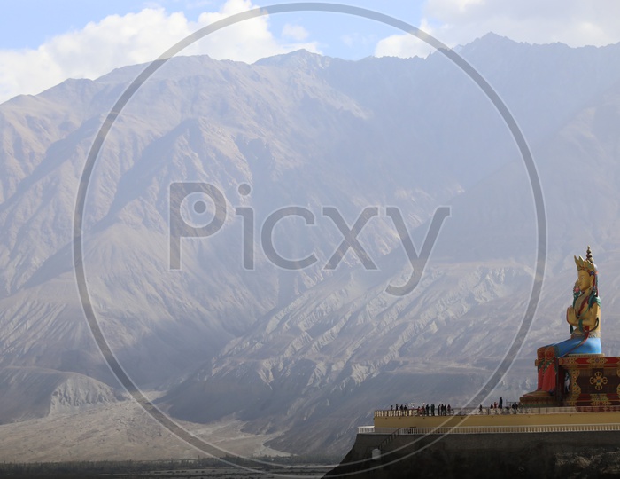 Statue of Buddha in leh with snow capped mountains in the background / Diskit Monastery, Diskit Gompa