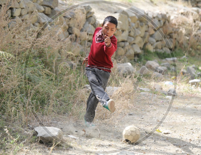 school kid playing football in leh