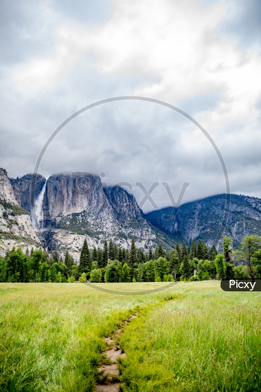 A Beautiful Composition Shot Of a Mountains In Yosemite Valley With Water fall , Mountains , Fields In Foreground and Sky With Clouds