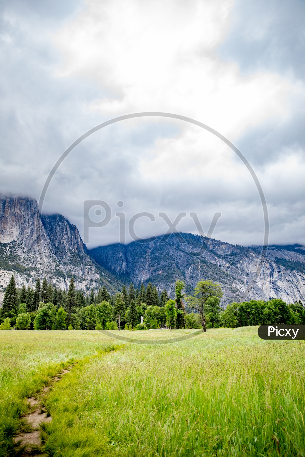 A Beautiful Composition Shot Of a Mountains In Yosemite Valley With Water fall , Mountains , Fields In Foreground and Sky With Clouds