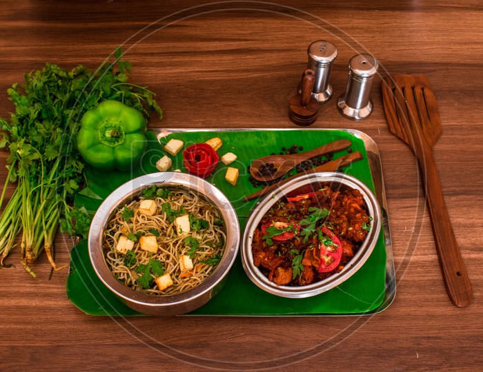 Veg Paneer Noodles and Gobi Manchurian Beautifully Presented Over a Plate Coposition Shot on a Wooden BackGround