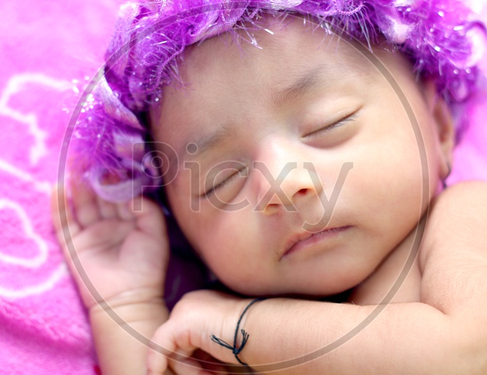Newborn baby girl with a flower hair band - Sleeping on the bed