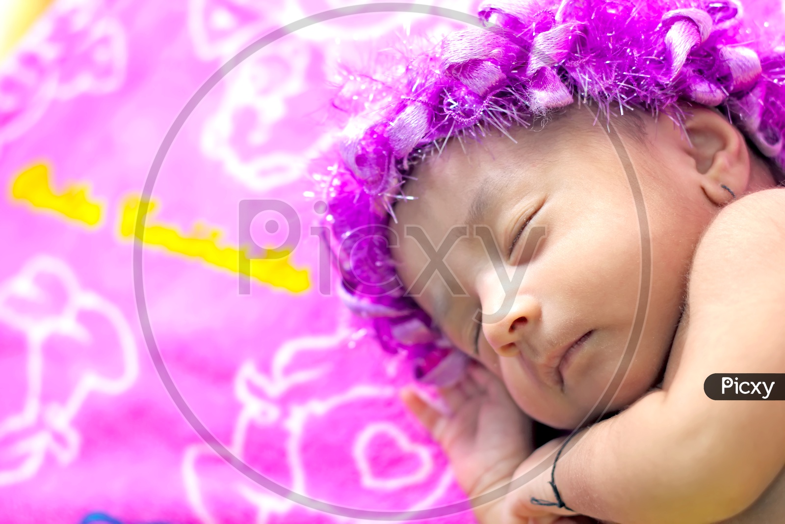 Newborn baby girl with a flower hair band - Sleeping on the bed