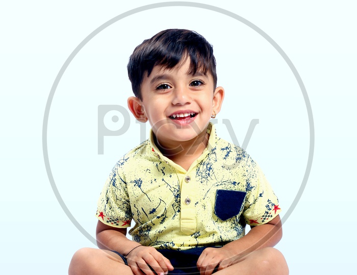Indian Boy Sitting and Smiling in An Isolated white Background