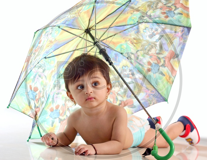 Baby girl crawling under the umbrella