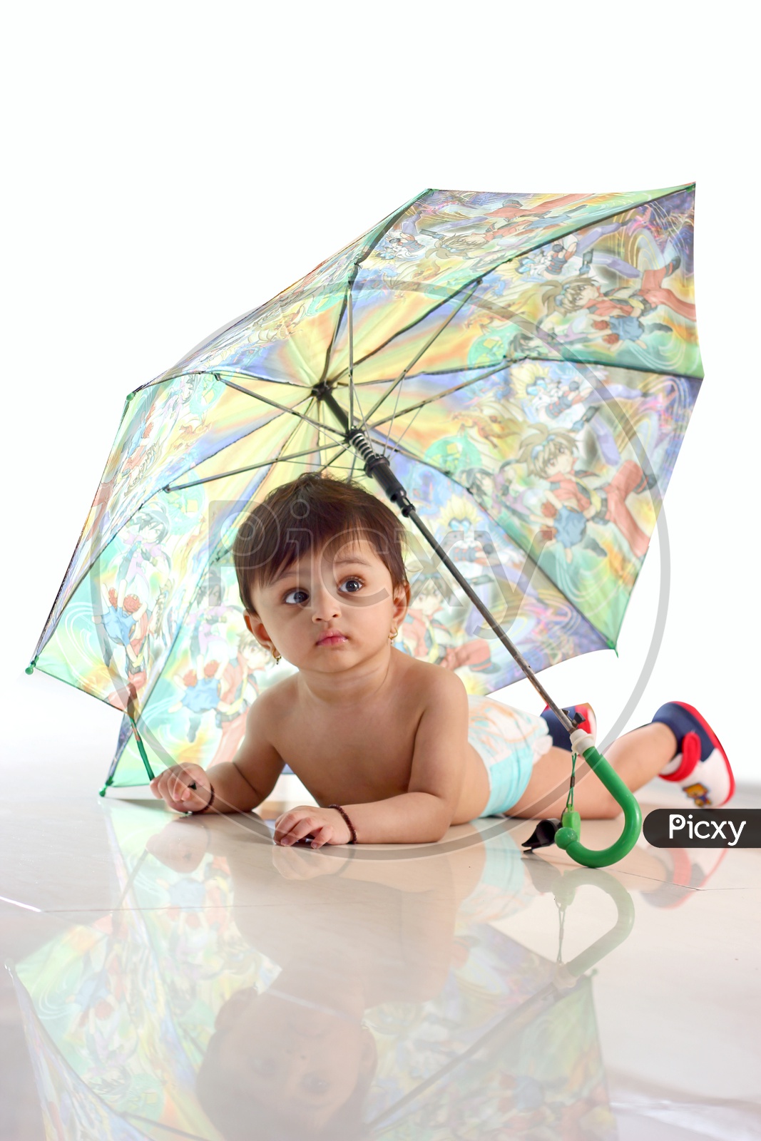 Baby girl crawling under the umbrella