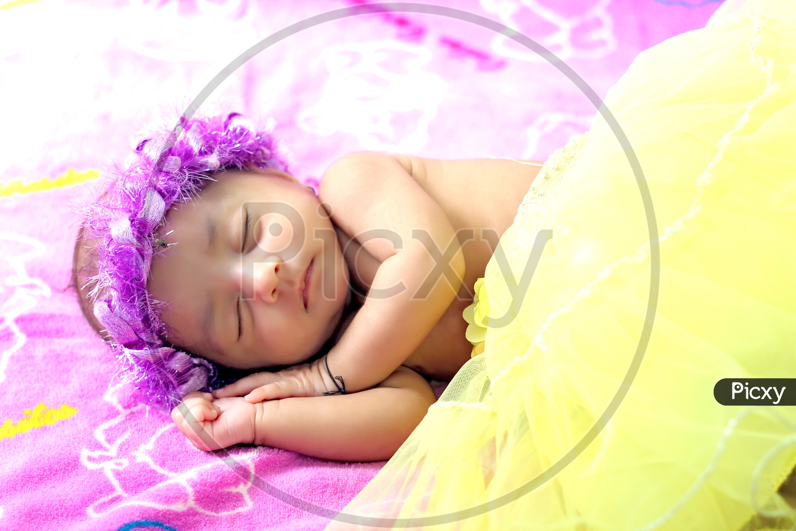 Cute new born baby girl with flower hair band lying down on the bed