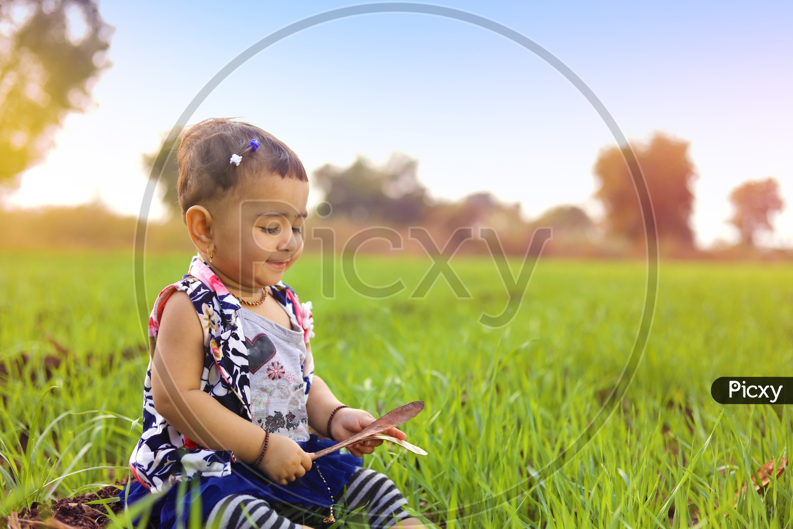 Baby girl is sitting in the middle of the agriculture fields and Playing with mud