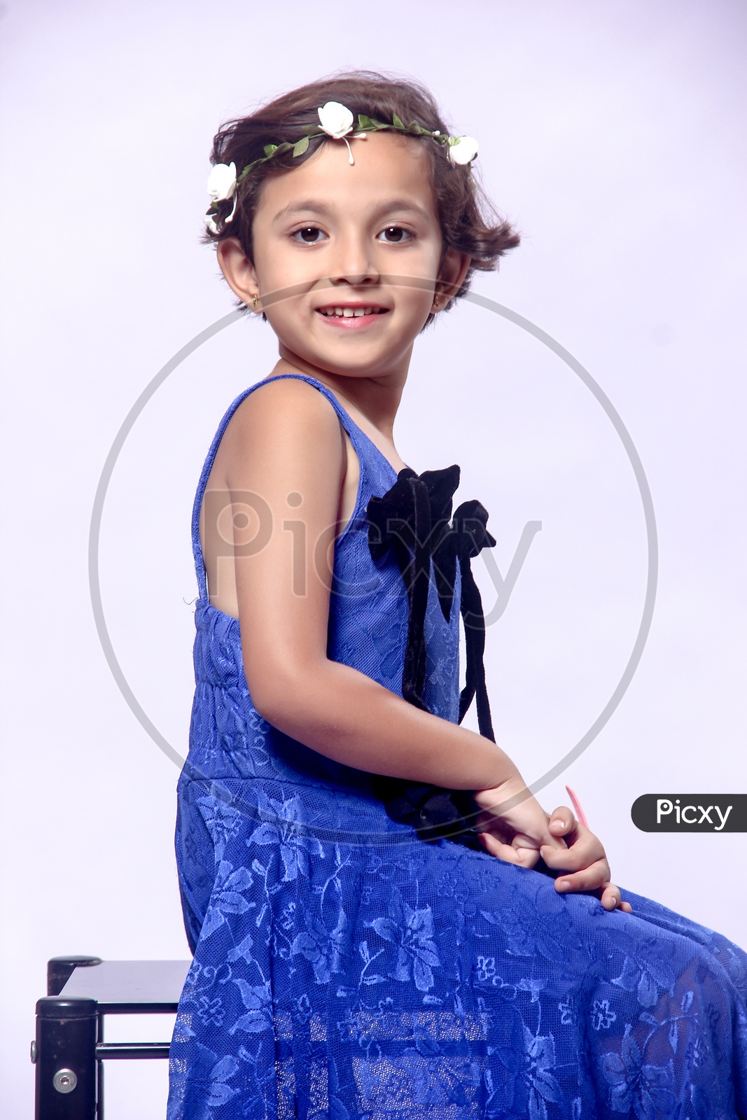 Girl dressed up in Blue frock with a Flower hair band