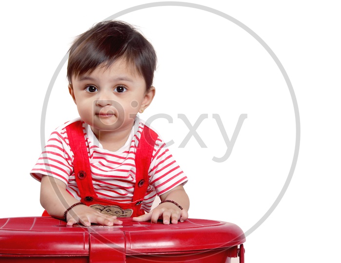 Cute baby girl in red dress plays with the basket