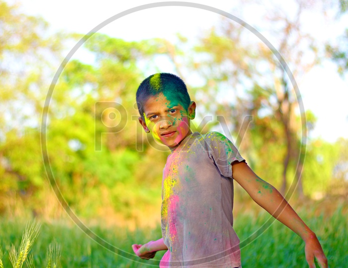 Boy with Holi colours/colors on face playing in the middle of the fields