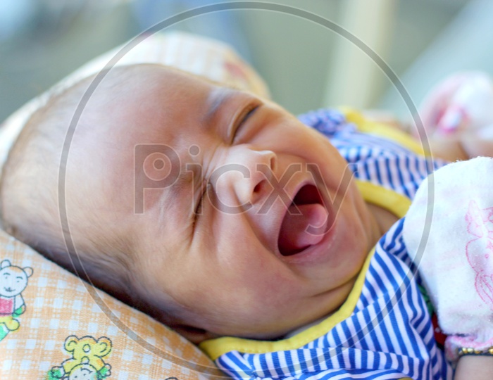 Portrait of a newborn baby crying on a bed