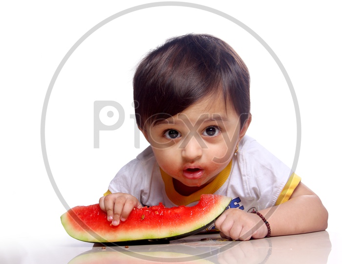 Baby girl making faces while eating watermelon