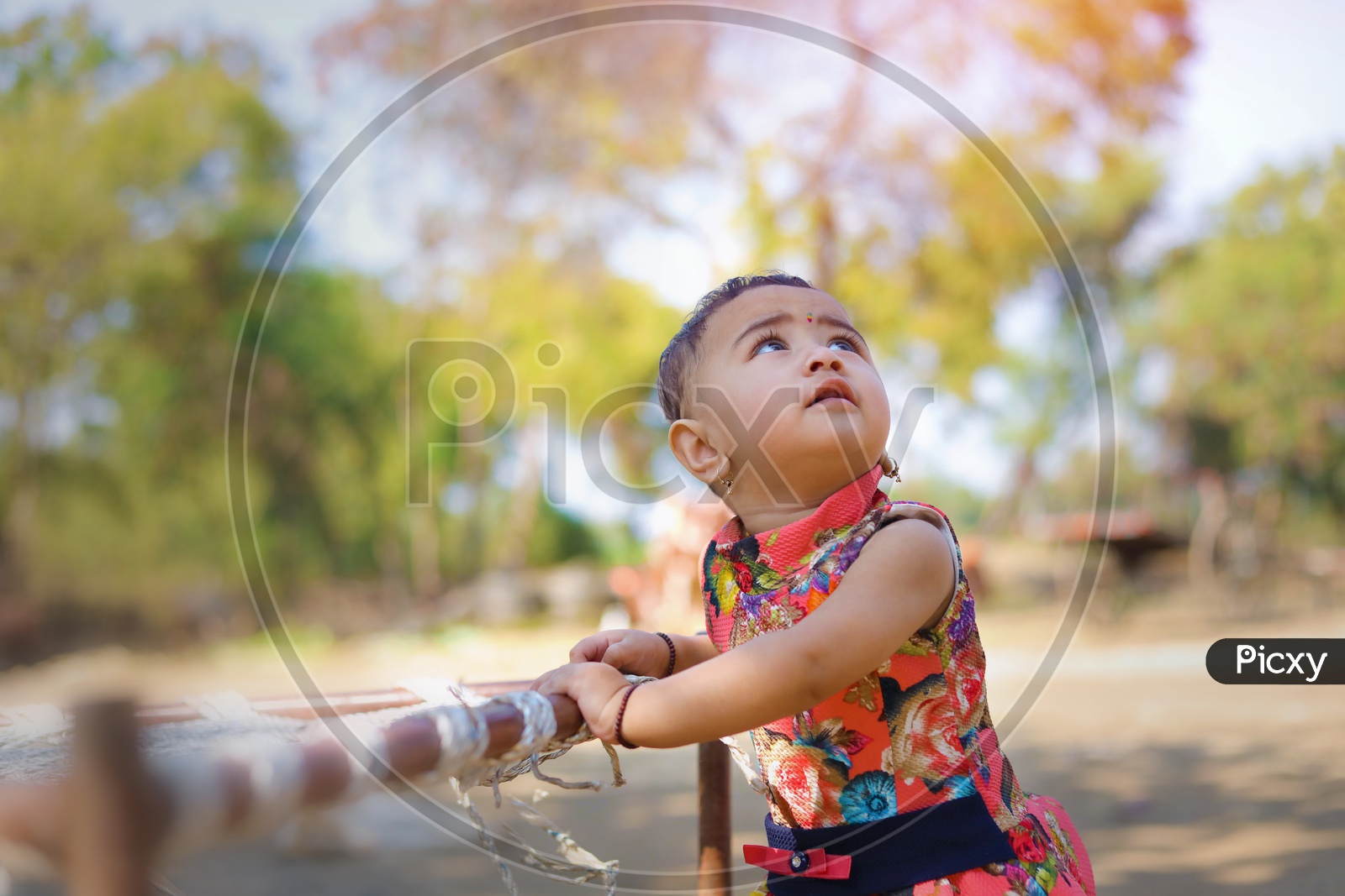 Baby girl playing with a flower near a cot