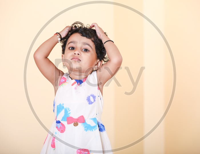 Indian girl dressed in colorful frock playing with her hair