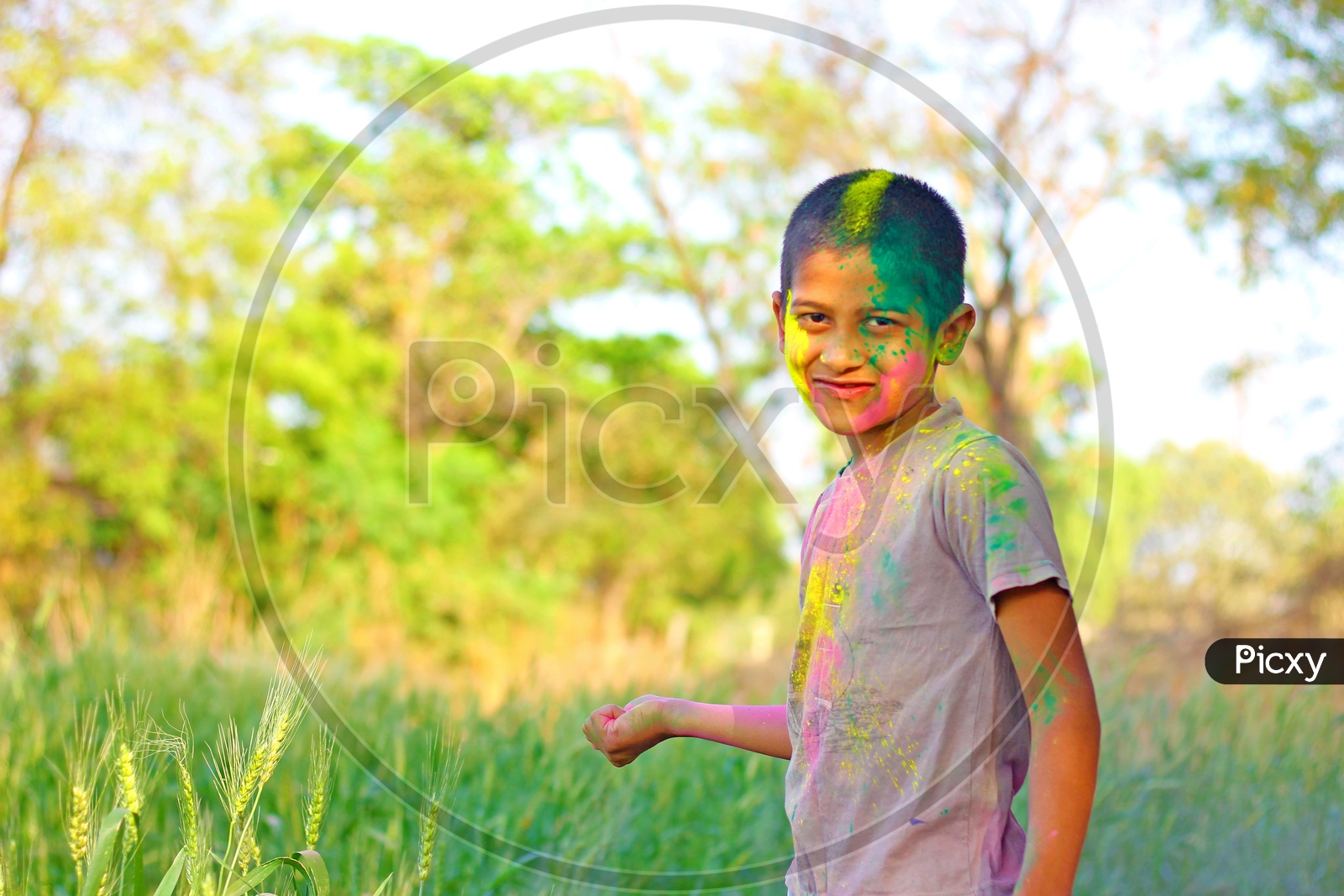 Boy with Holi colours/colors on face playing in the middle of the fields