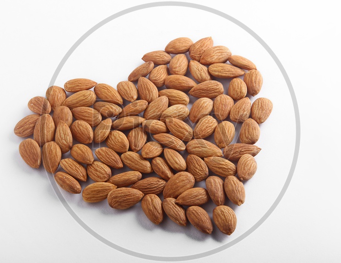 Tasty almonds on white background with love shaped design