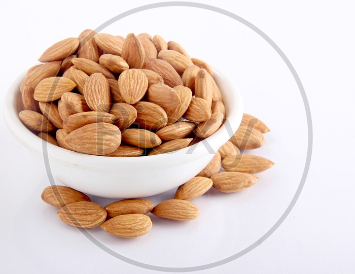 Tasty almonds in a bowl on white background